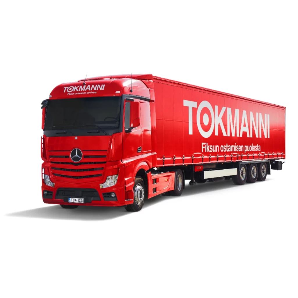 Kokopunainen suuri rekka teksteillä "Tokmanni" jonka alapuolella hieman pienemmällä "Fiksun ostamisen puolesta". Tekstit lukevat rekan kyljessä kuin myös kuskin yläpuolella olevassa tilassa rekan etuosassa.