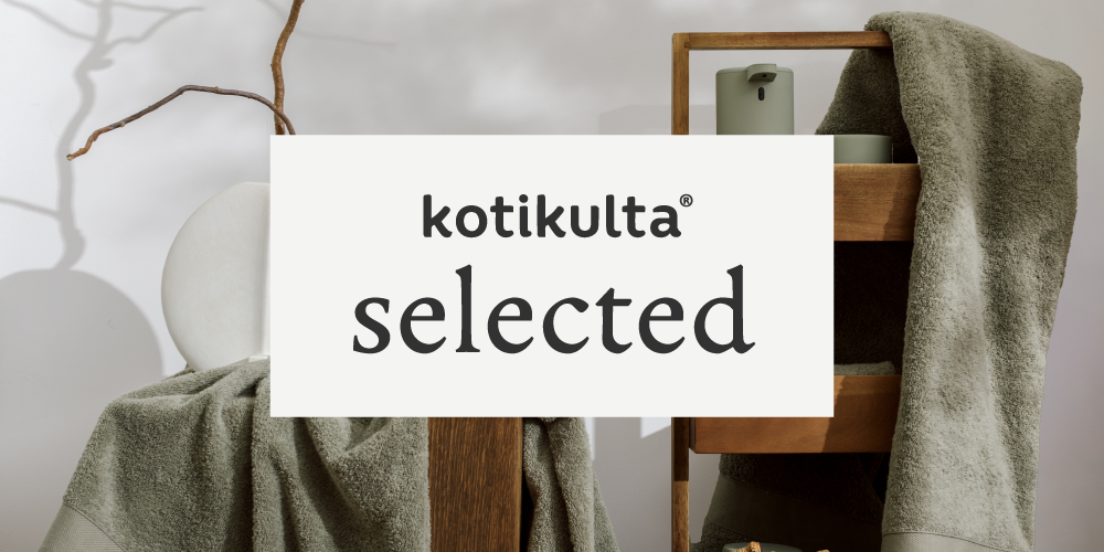 Esimerkki visuaalisesta brändikäytöstä: Kotikulta Selected -logo valkoisella pohjalla aseteltuna sisustuskuvan päälle, jossa esillä vihreänharmaita pyyhkeitä ja puisia hyllyjä.