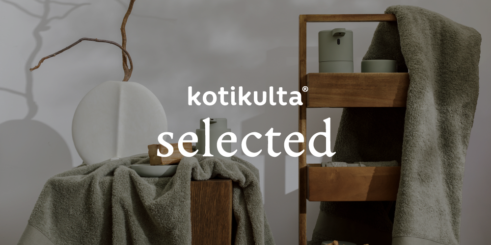 Esimerkki Kotikulta Selected -brändikuvan visuaalisesta käytöstä: sisustuksellinen kuva vihreänharmaista pyyhkeistä ja puisista hyllyistä, jonka päälle on lisätty valkoisella bränditeksti “Kotikulta Selected”.