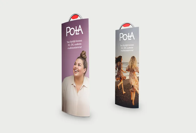 Kuvassa on valkoisella taustalla kaksi myymälämainosta, joissa esitellään Tokmannin Pola-vaatemallistoa. Vasemmalla olevassa mainoksessa vaaleanvioletilla taustalla hymyilee nuori nainen, ja mainoksessa lukee valkoisella: "Pola – Tee löytöjä koossa XS–3XL uudesta mallistostamme!" Oikeanpuoleisessa mainoksessa on kuva kahdesta naisesta juoksemassa rannalla, ja siinä on sama Pola-logo ja viesti. Molemmat mainokset ovat muodoltaan kaartuvia, ja niiden yläosassa näkyy punainen Tokmanni-logo. Kuvassa korostuu iloinen ja kehopositiivinen viestintä sekä malliston monipuolisuus.