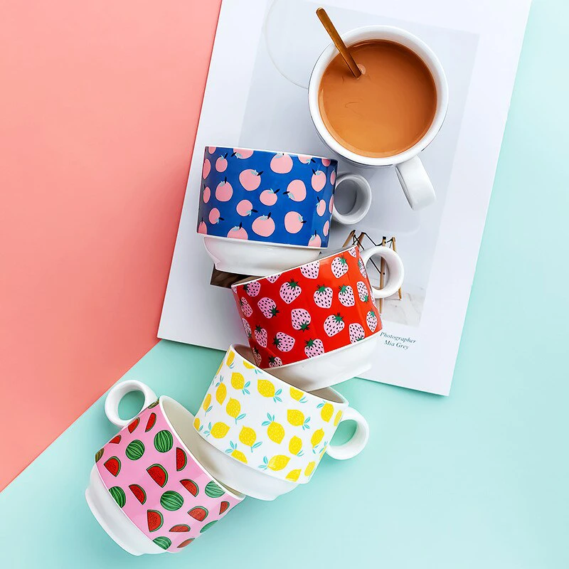 Product image of colorful Miny mugs with fruit patterns, arranged against a pastel-toned background divided into different color blocks